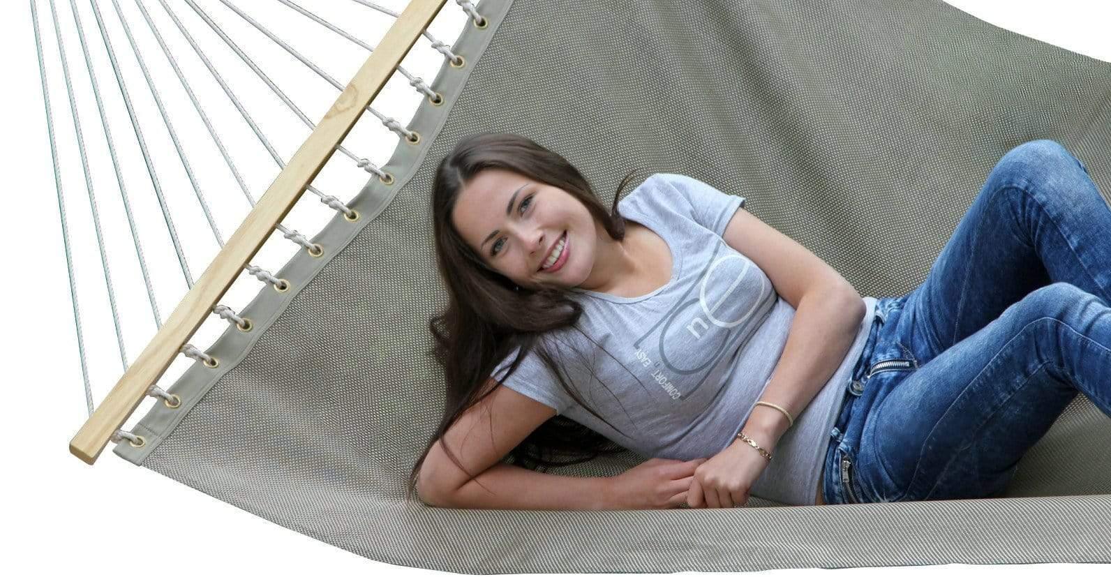 Woman relaxing on a grey double hammock, casual outdoor lounge setting