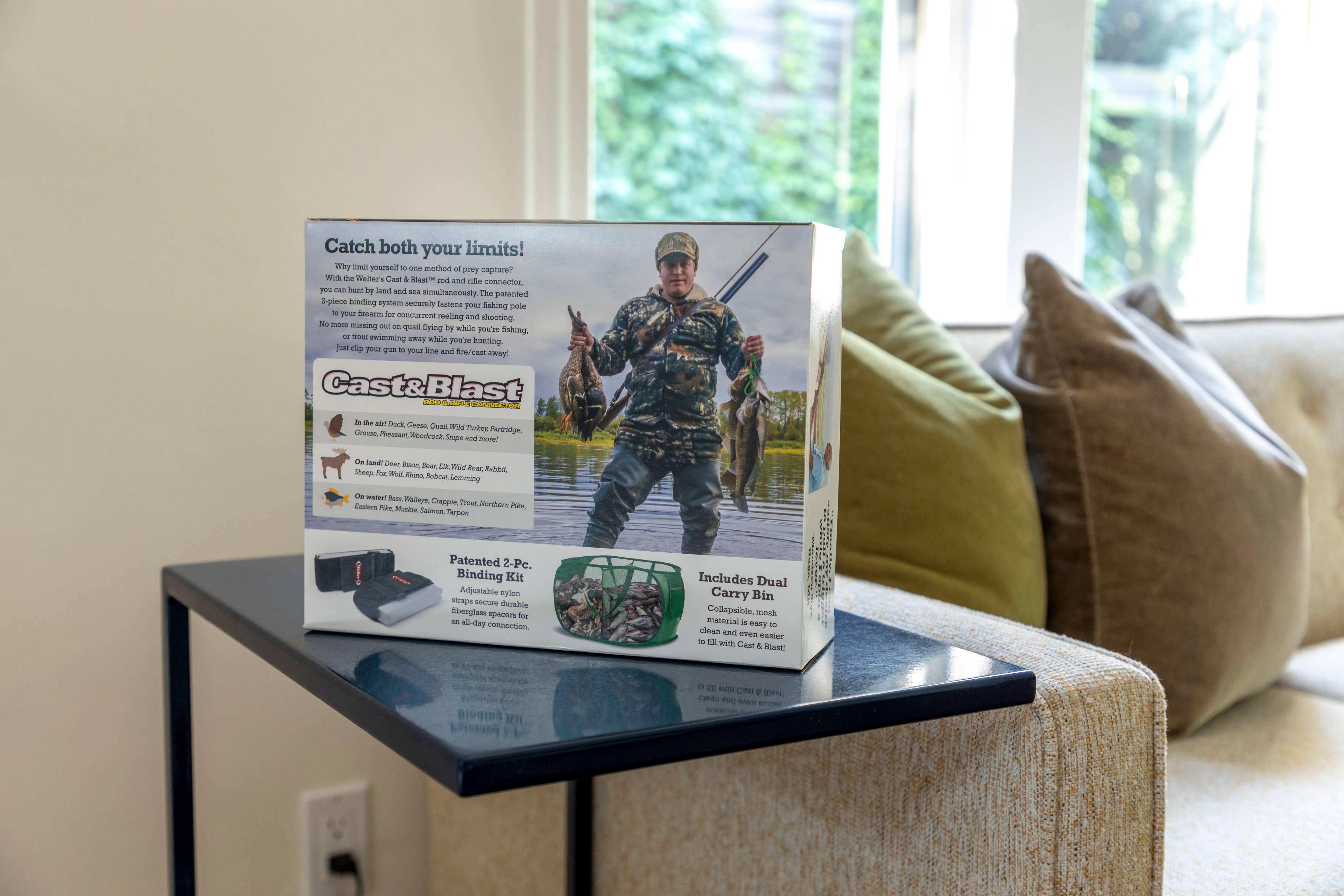 Cast & Blast product box with hunter and fishing gear on a living room table with pillows