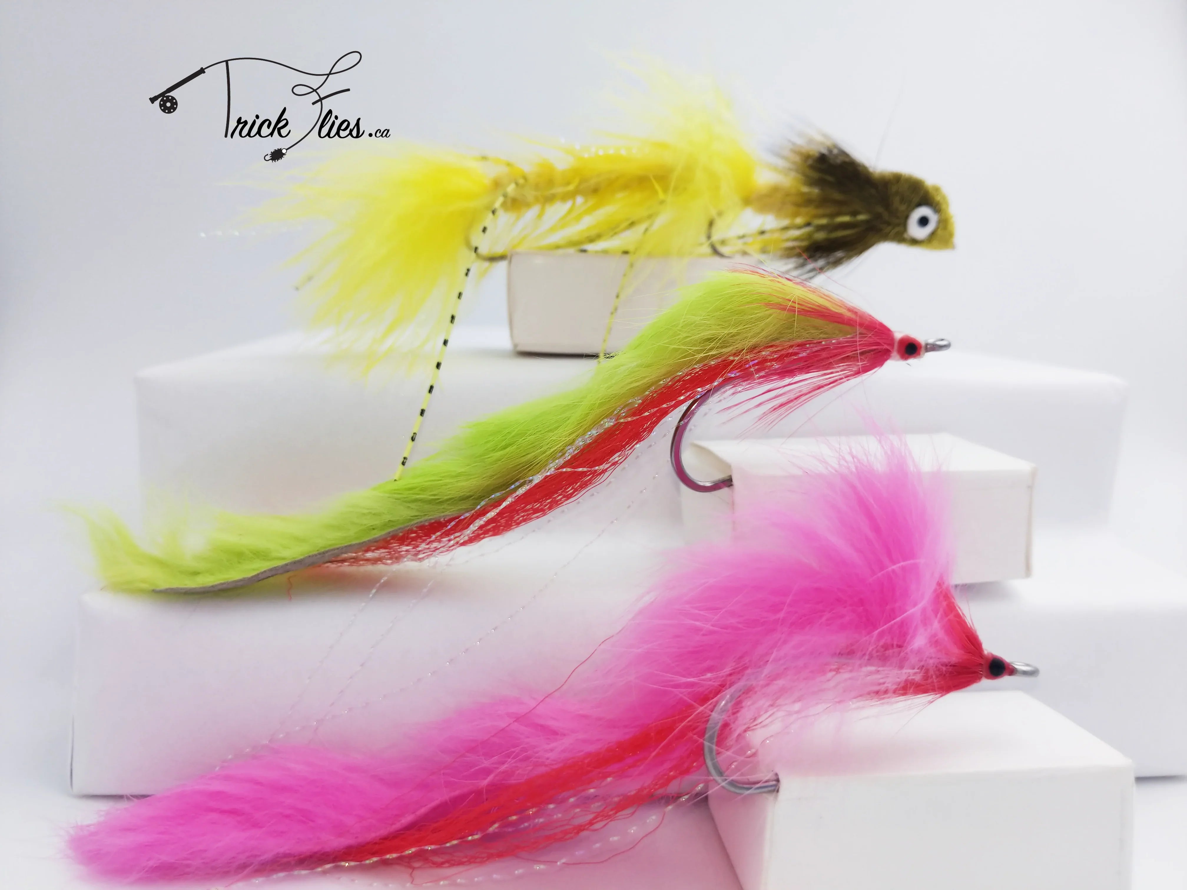 Colorful pike bunny streamer flies in yellow, green, and pink on white display blocks