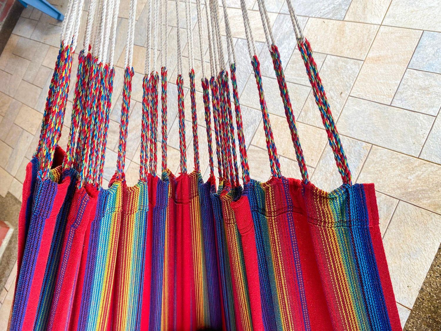 Colorful striped hammock with braided ropes hanging indoors on tiled floor