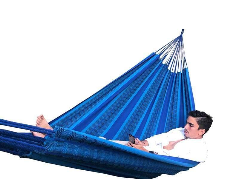 Man relaxing in a blue and black Brazilian double hammock against a white background