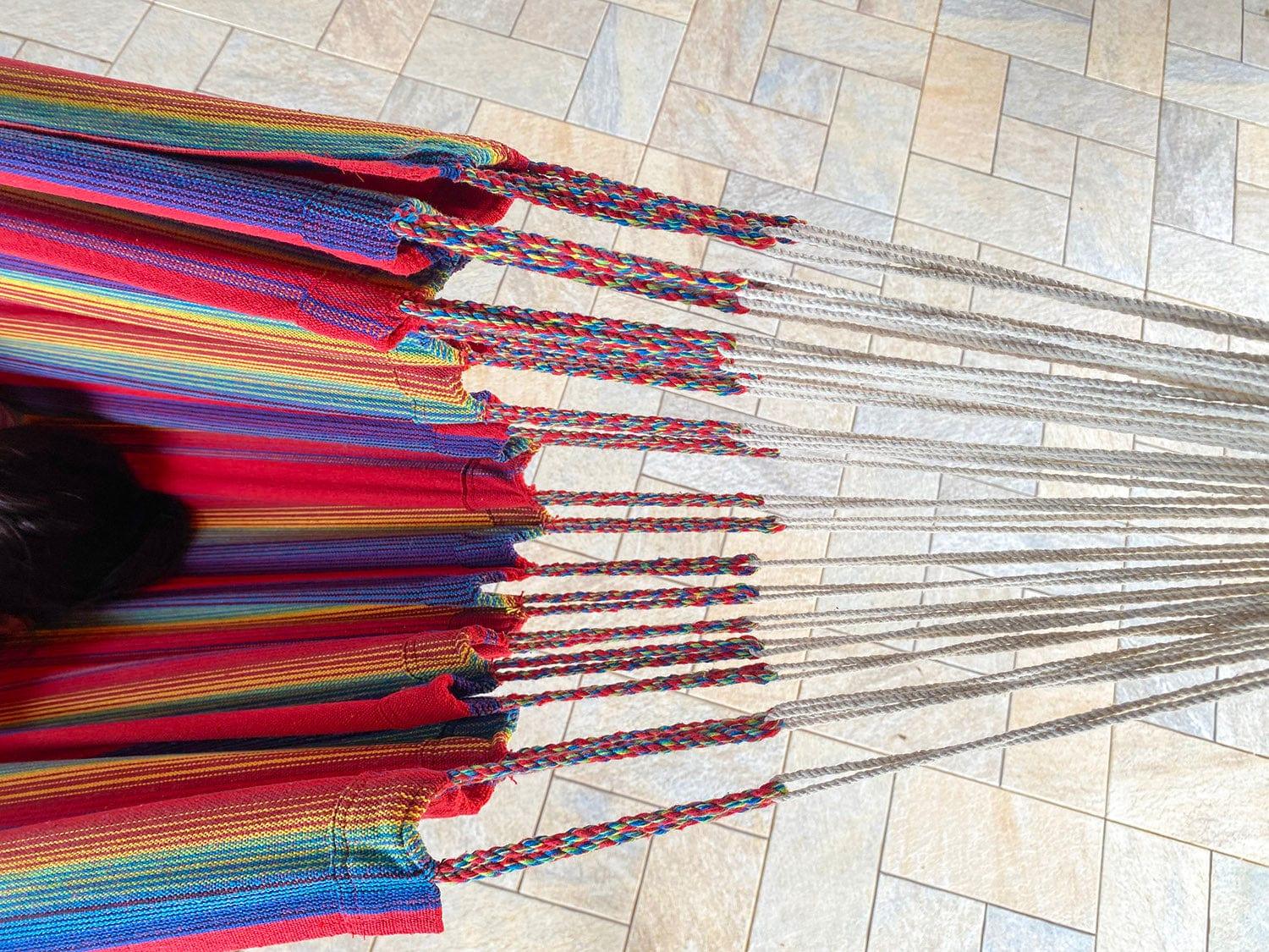 Colorful striped hammock with braided ropes on a tiled patio floor