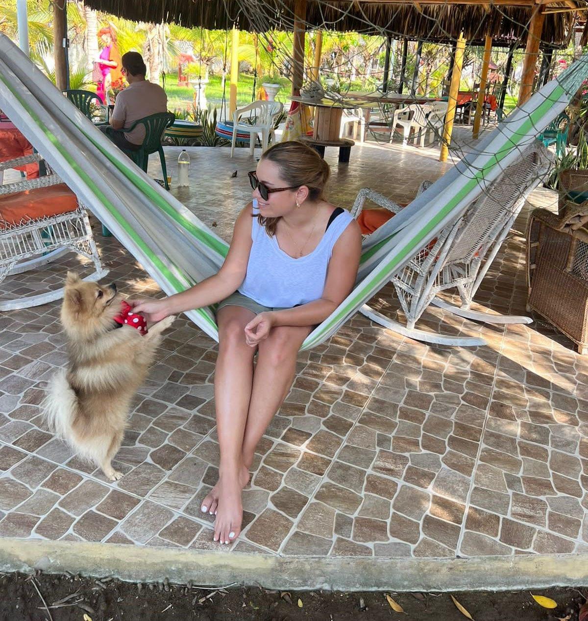 Woman relaxing on a green, grey, and white Brazilian hammock on a tiled patio.