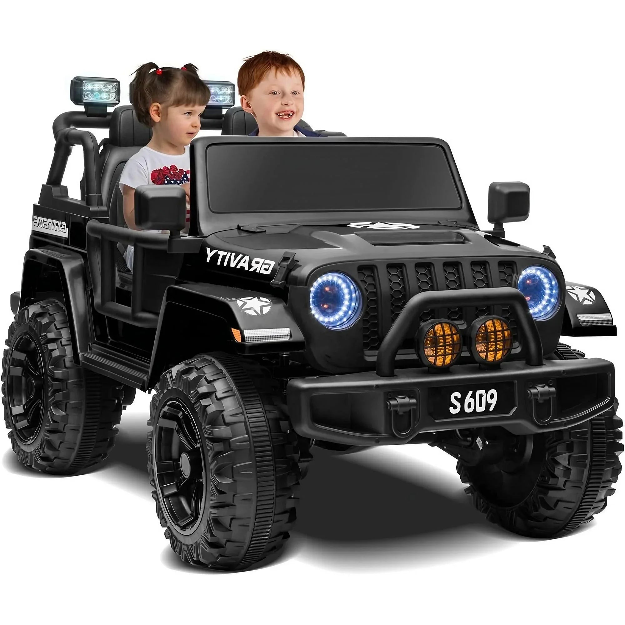 Two kids riding in a black electric toy Jeep with off-road tires and LED headlights