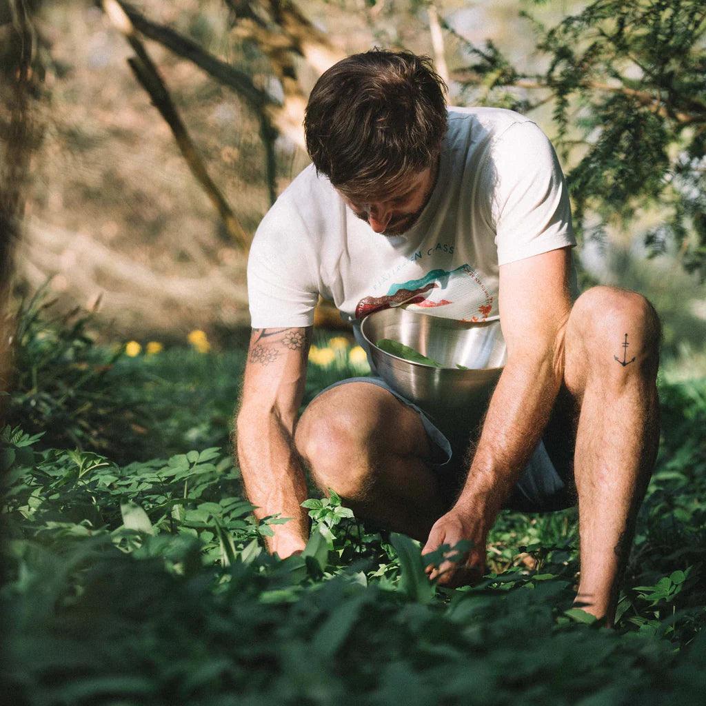 Man foraging wild greens outdoors with stainless steel Primus Campfire bowl in forest
