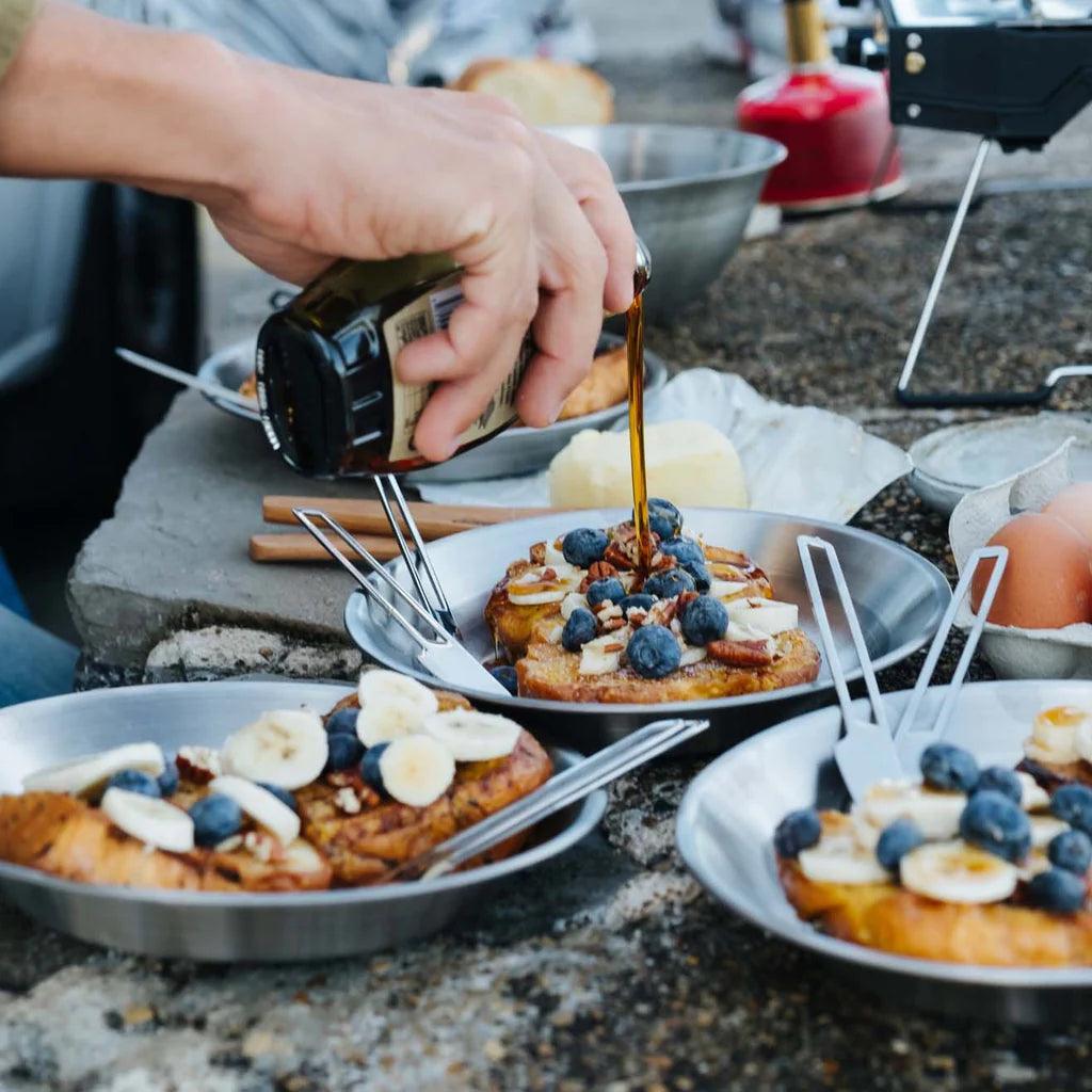 Campfire serving kit with French toast, blueberries, bananas, and syrup outdoors
