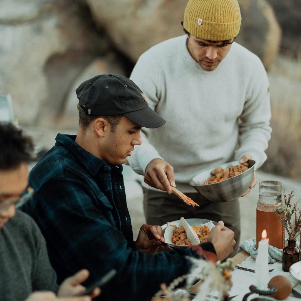 People enjoying an outdoor meal with Primus Campfire Serving Kit at a rustic campsite table