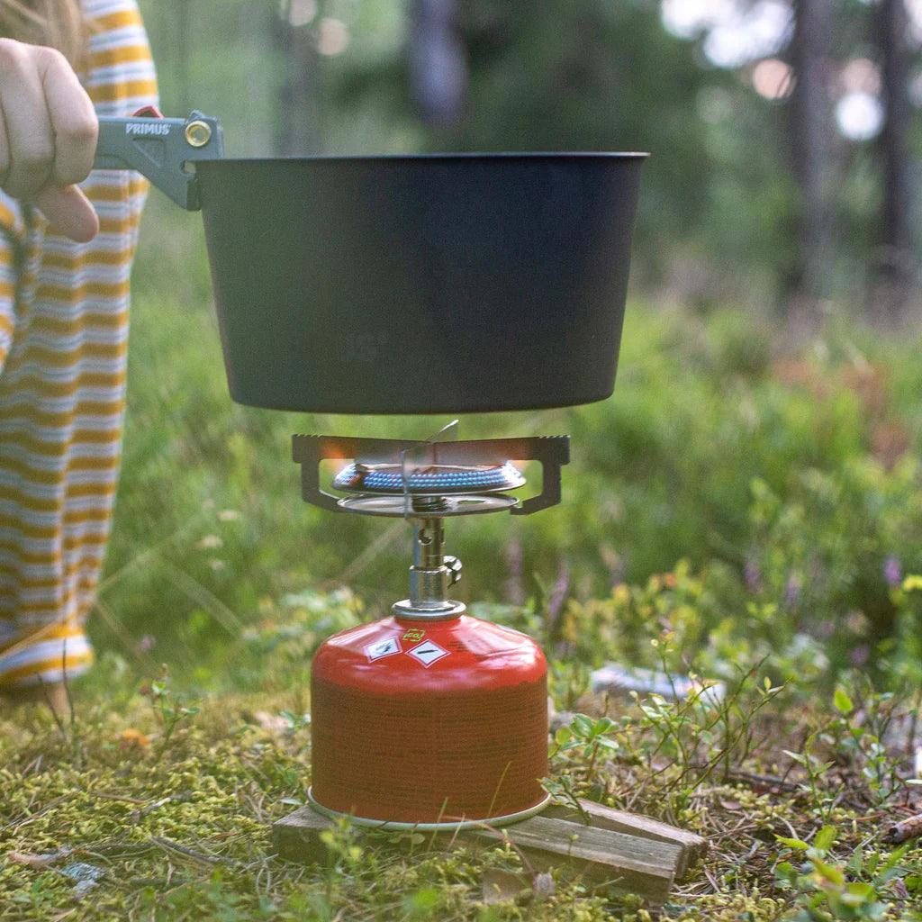 Primus camping stove with pot on gas burner in forest setting