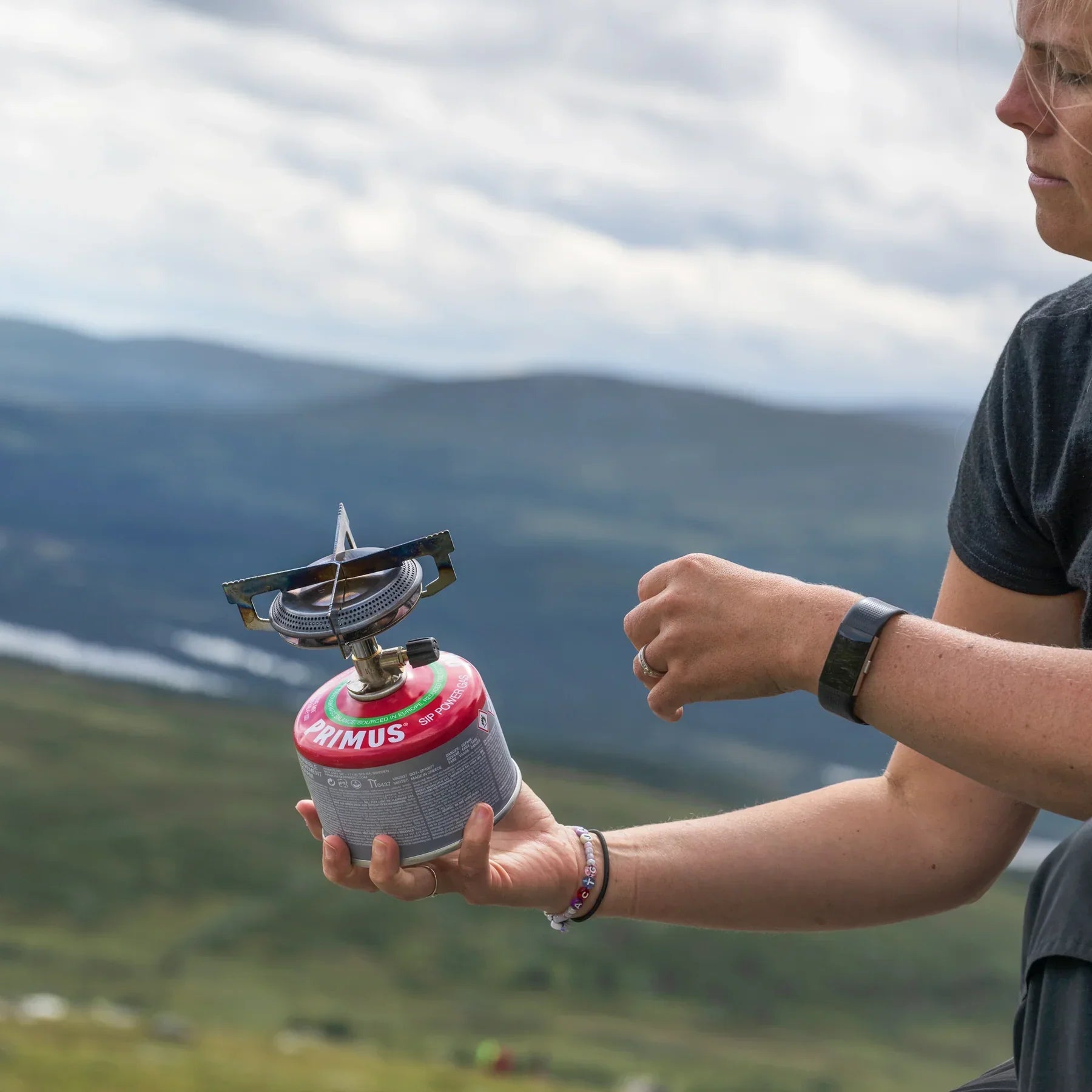Person holding Primus Mimer camping stove outdoors in mountains