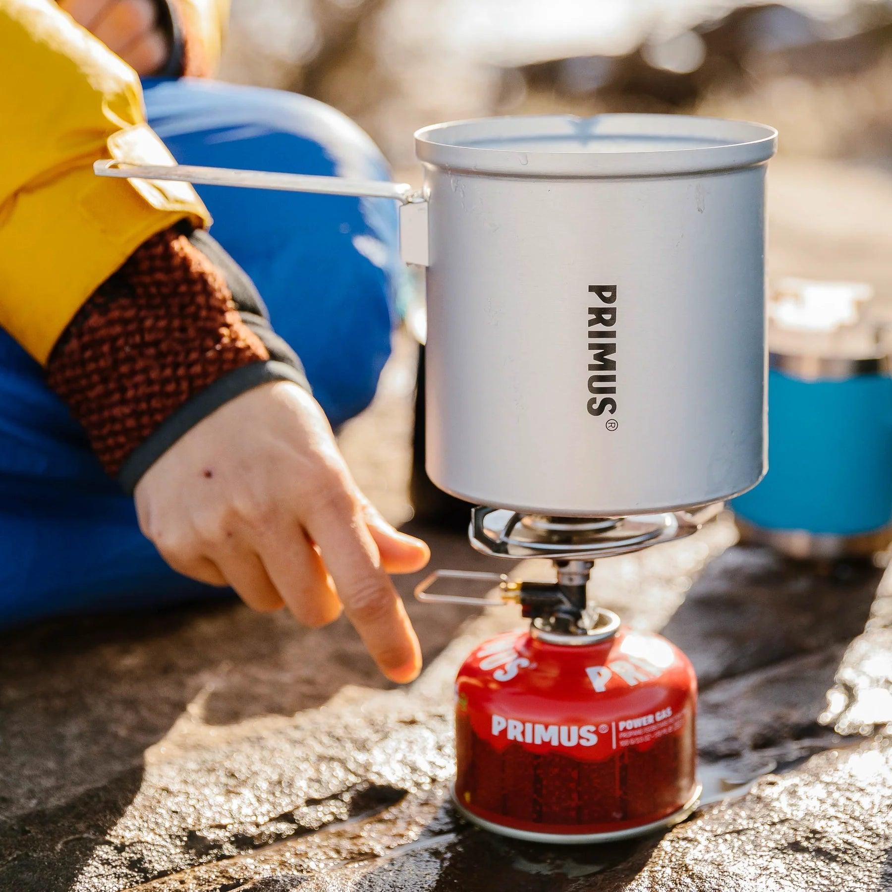 Primus Essential Trail Stove with pot and gas canister on rocky outdoor surface
