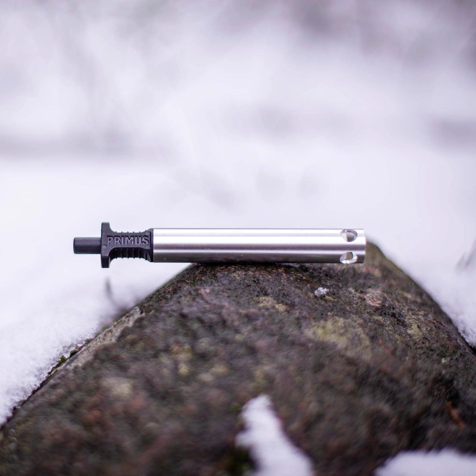 Primus piezo igniter stick for outdoor camping, resting on a snowy rock