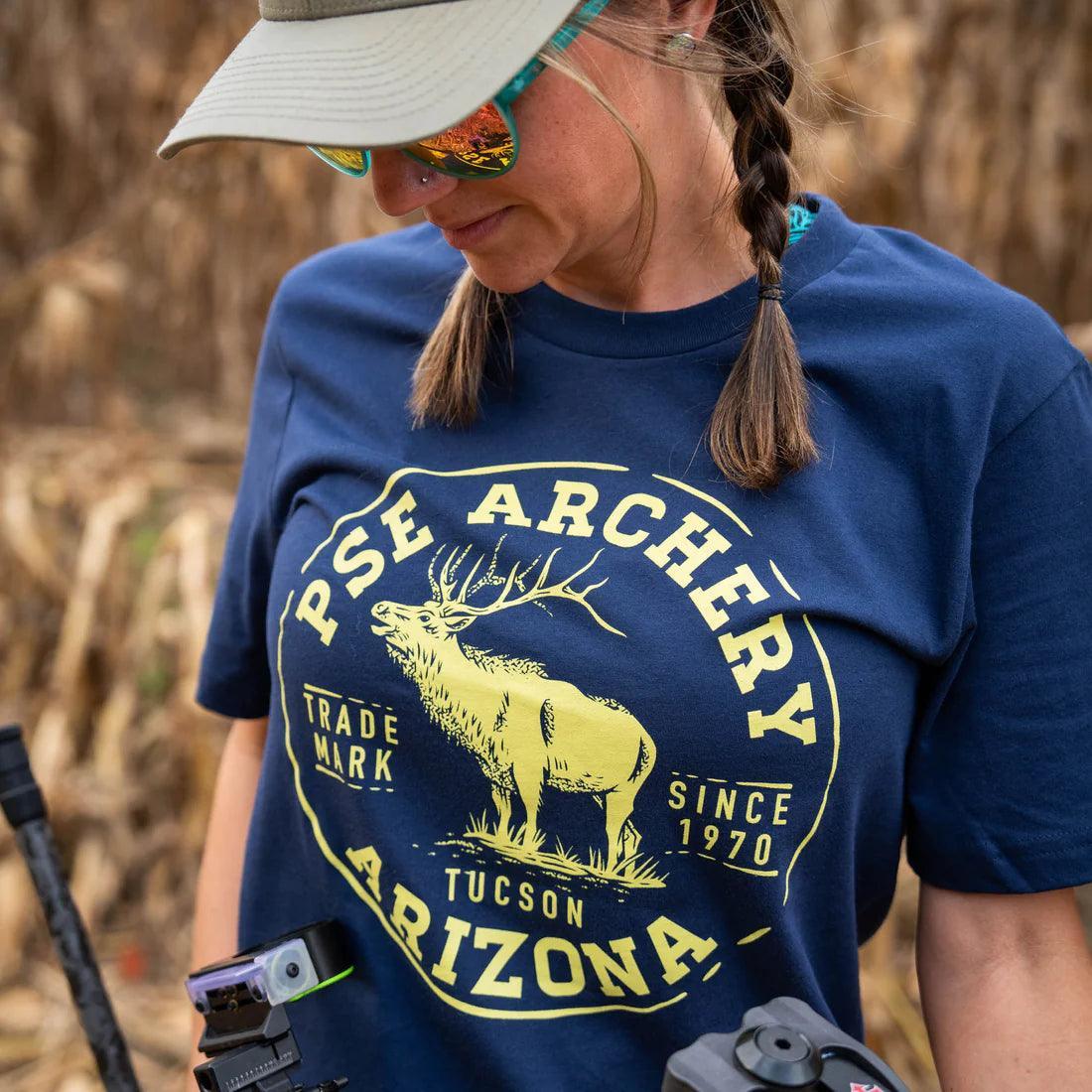 Woman in navy PSE Archery Arizona elk logo t-shirt outdoors with camera gear