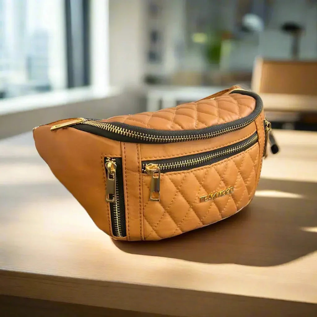 Quilted brown sheep leather waist bag with gold zippers on a table in sunlight