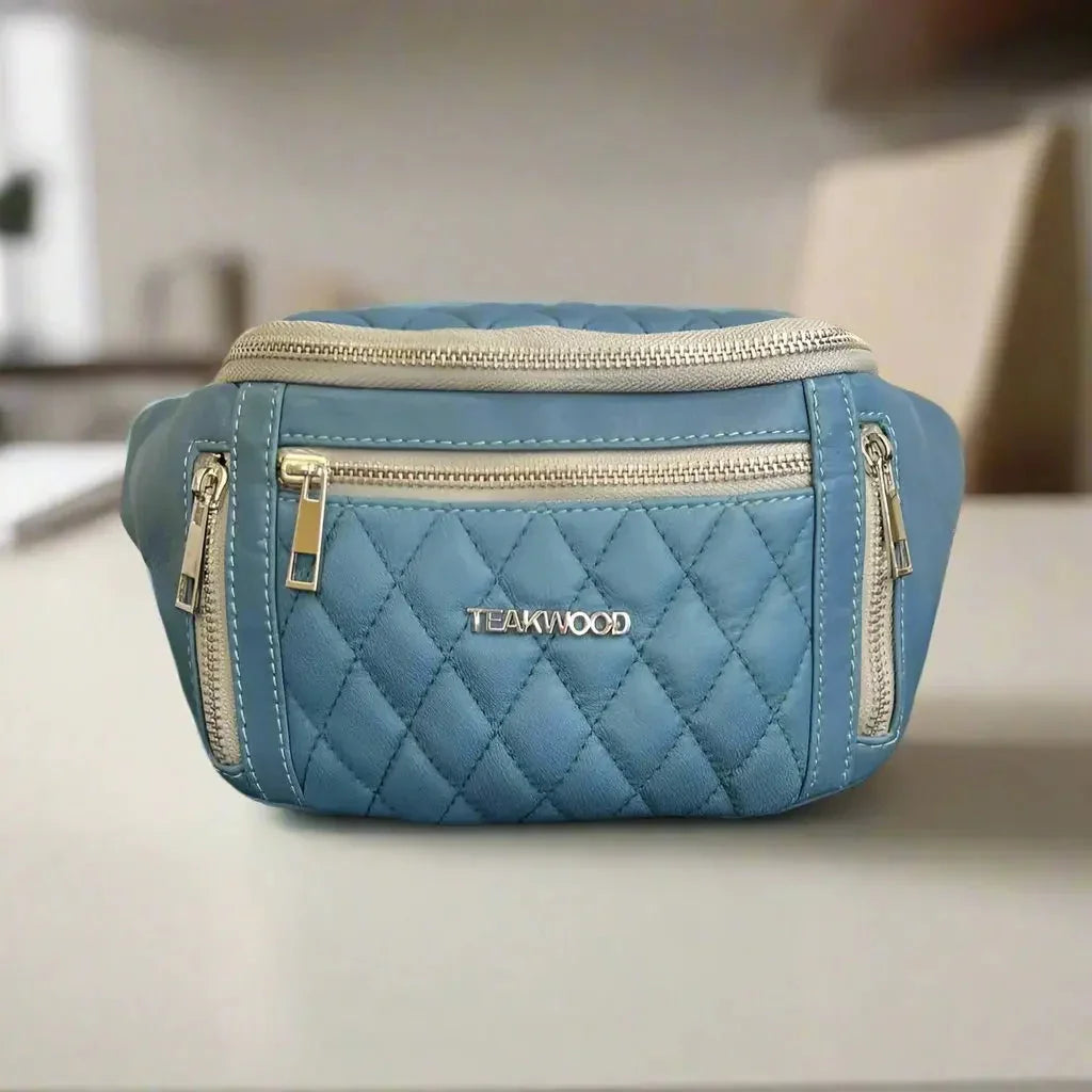Blue quilted sheep leather waist bag with silver zippers and Teakwood branding on a table.