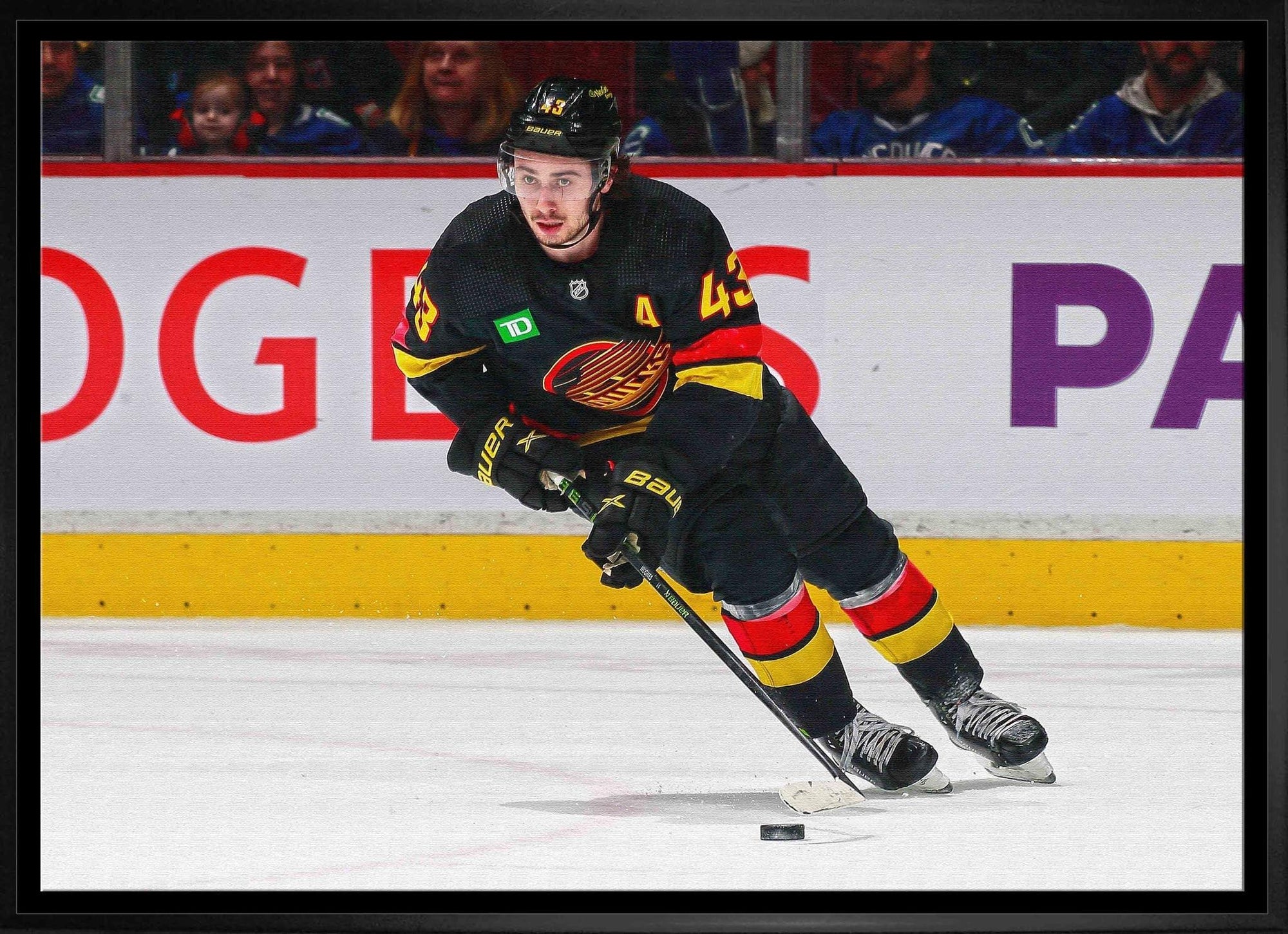 Ice hockey player in black Vancouver Canucks uniform skating on rink with puck