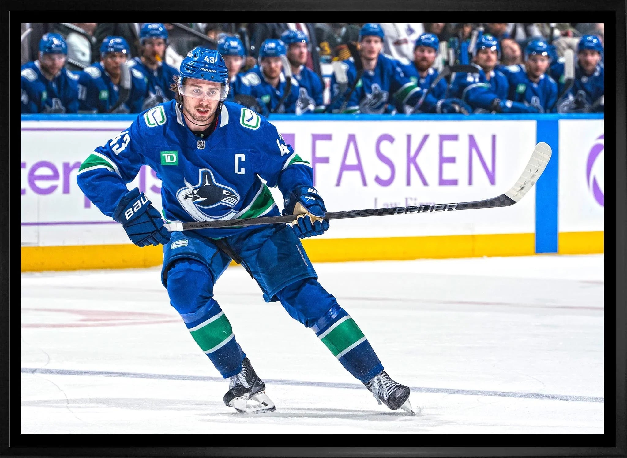Vancouver Canucks ice hockey player skating on rink during game, teammates in background
