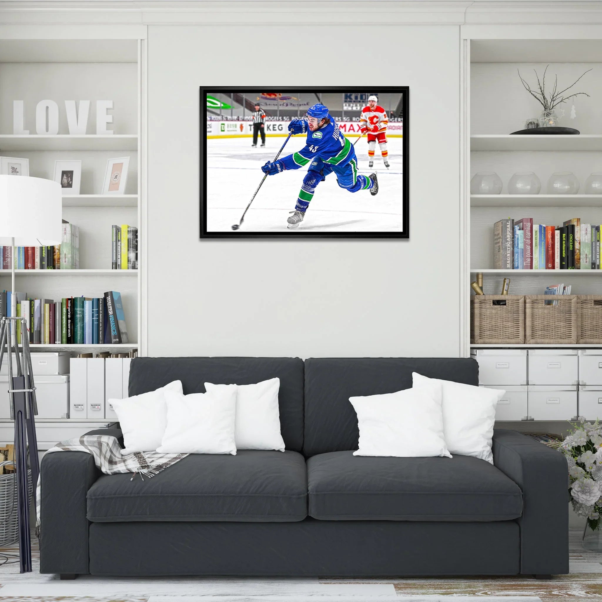 Modern living room with dark sofa, white pillows, and framed hockey artwork on the wall