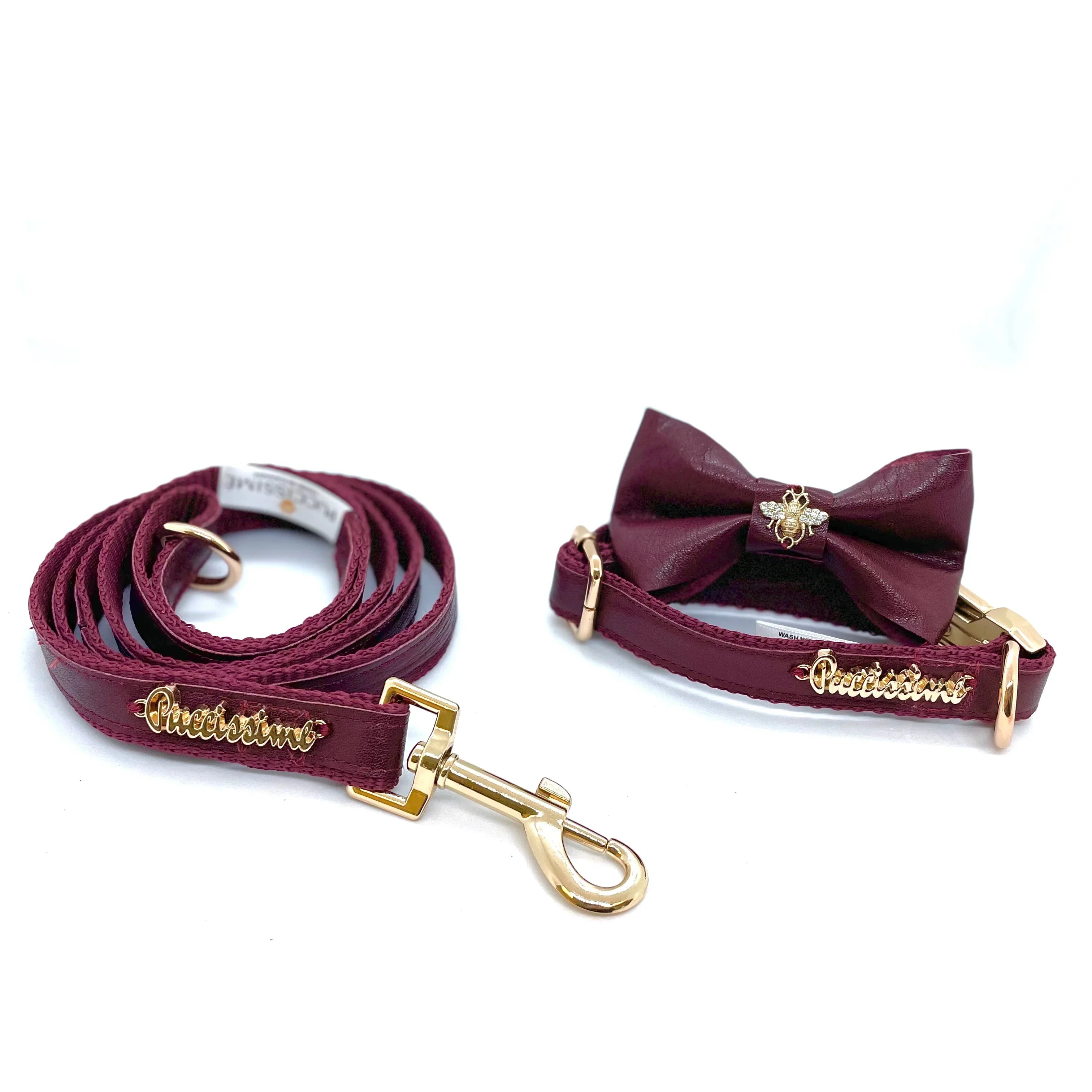 Burgundy leather dog leash and collar set with gold hardware and bow tie on white background