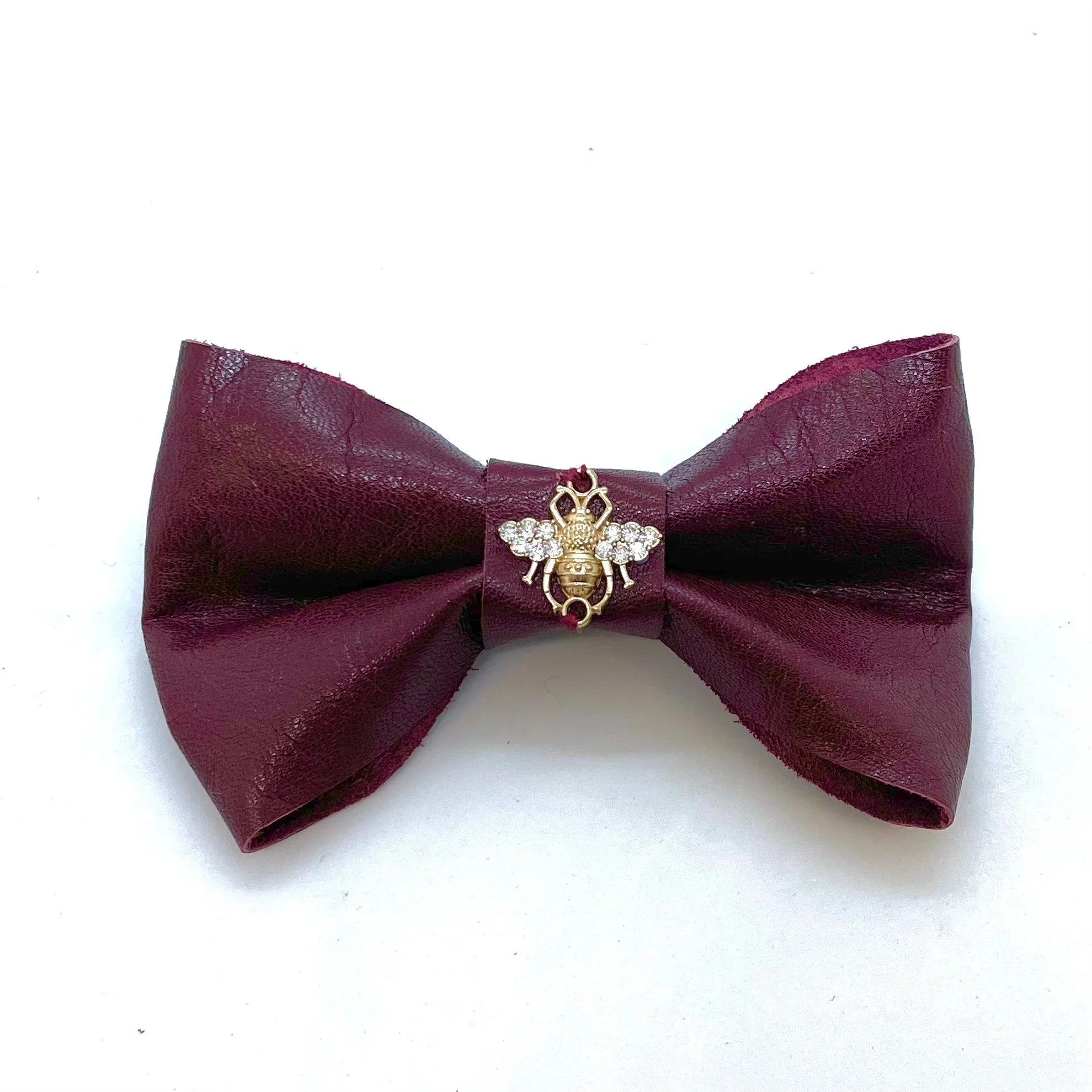 Burgundy leather bow tie with jeweled bee brooch on white background