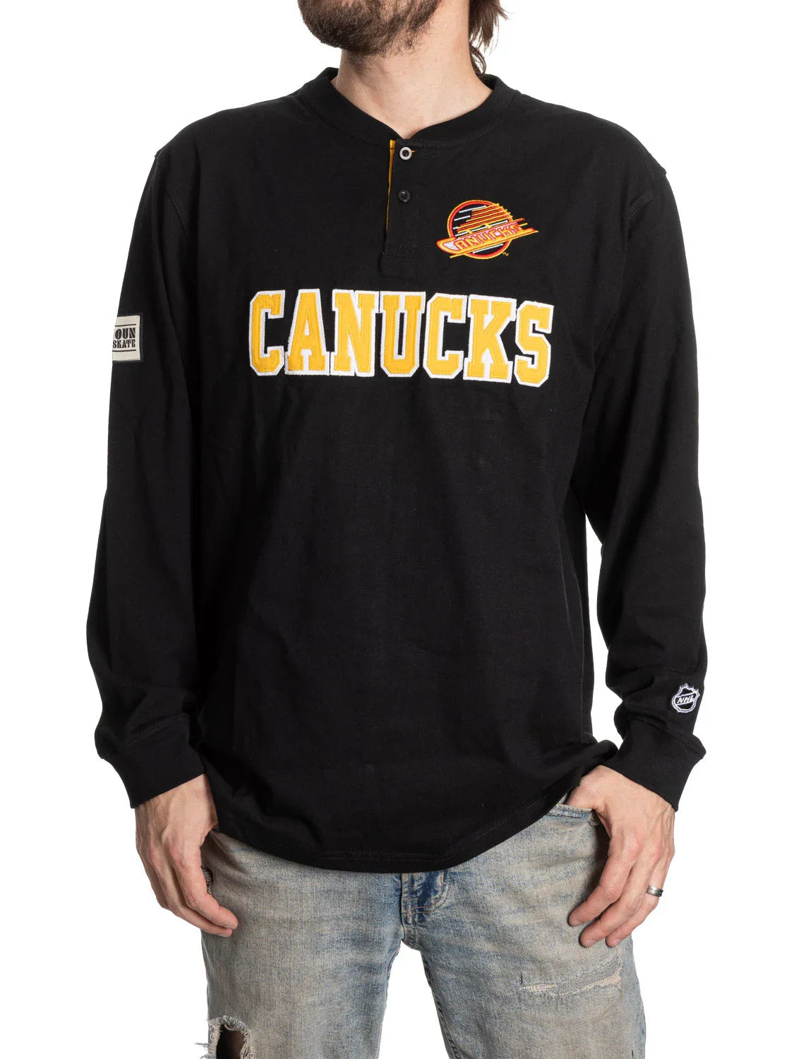 Man wearing black Vancouver Canucks henley shirt with yellow logo and distressed jeans