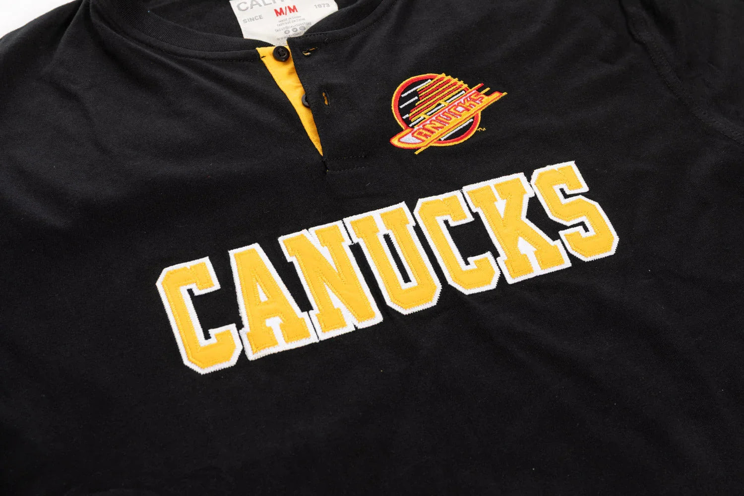 Vancouver Canucks black henley shirt with yellow NHL logo and CANUCKS embroidered text