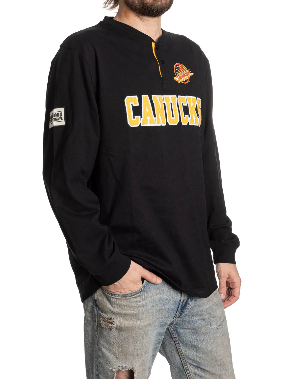Man wearing black Vancouver Canucks henley shirt and ripped denim jeans