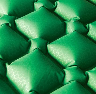 Close-up of green inflatable pad with hexagonal pattern and air cells for camping or outdoors