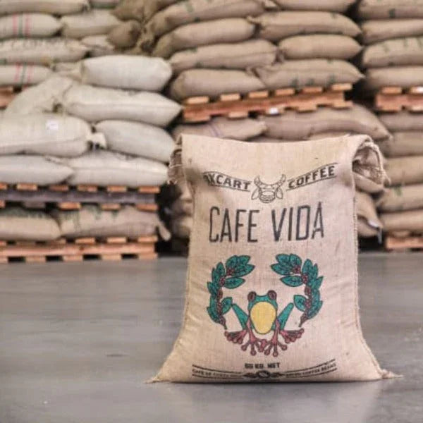 Cafe Vida Costa Rica coffee burlap sack with frog logo in warehouse, stacked coffee bags