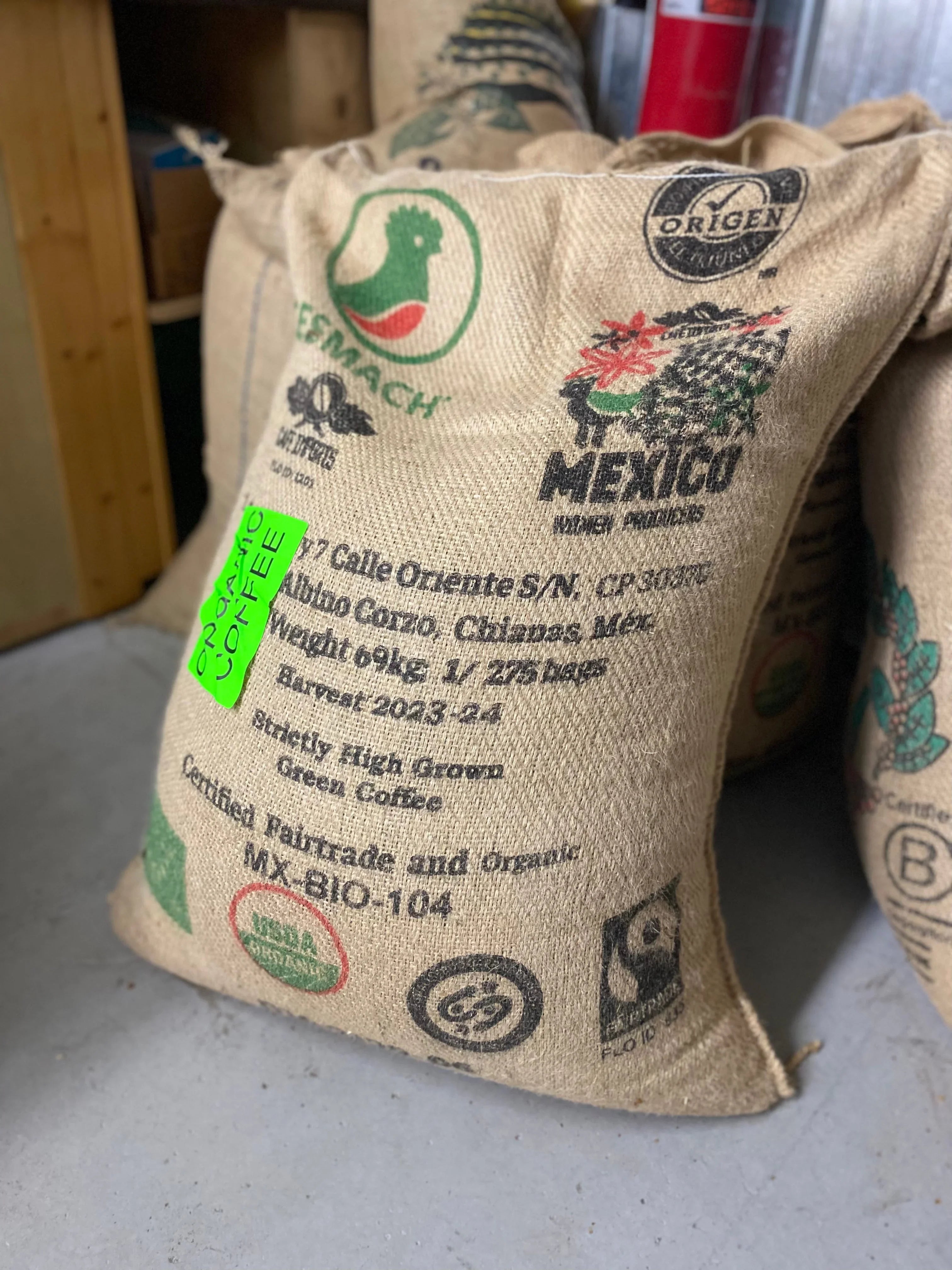 Large burlap sack of organic Mexican green coffee beans with Fairtrade and certification labels