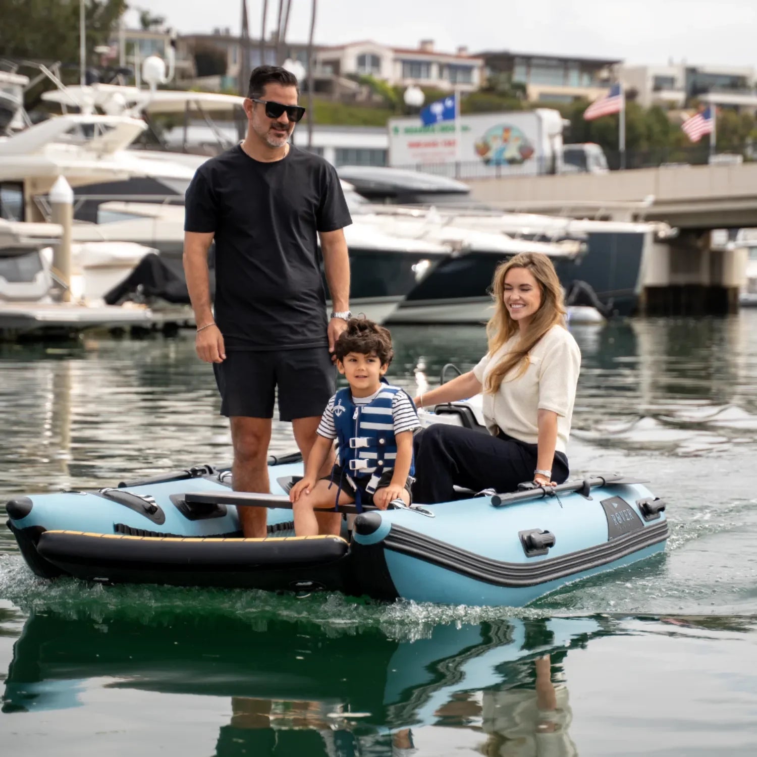 Family enjoying Rover Marine Battle Cat inflatable boat on calm marina waters
