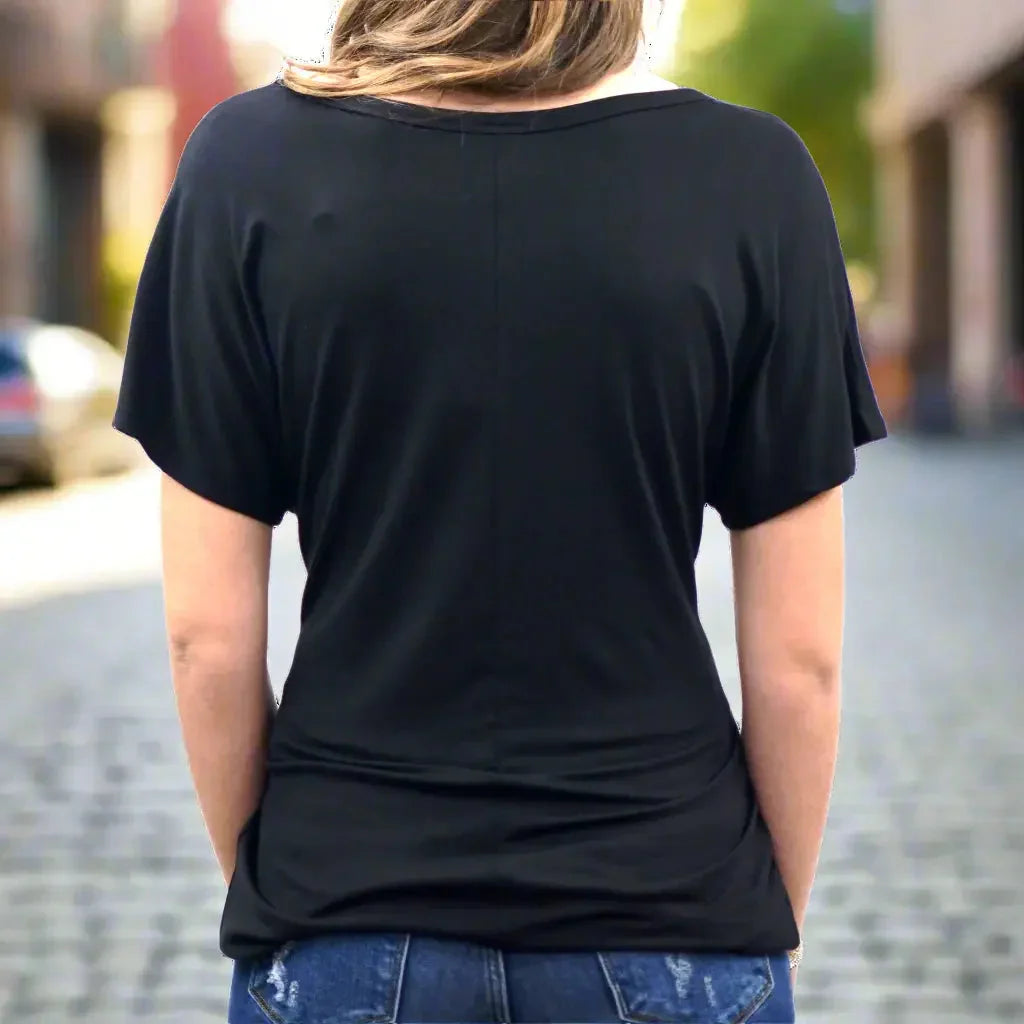 Back view of woman wearing black scoop neck tee and jeans outdoors