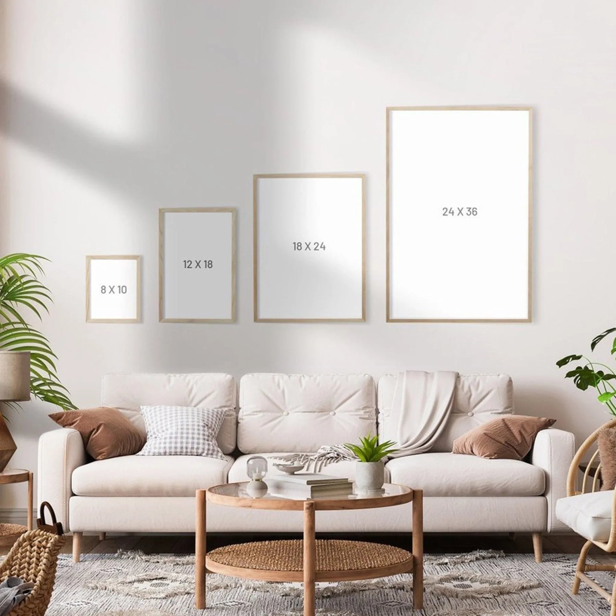 Living room wall with four blank picture frames in various sizes above a white sofa