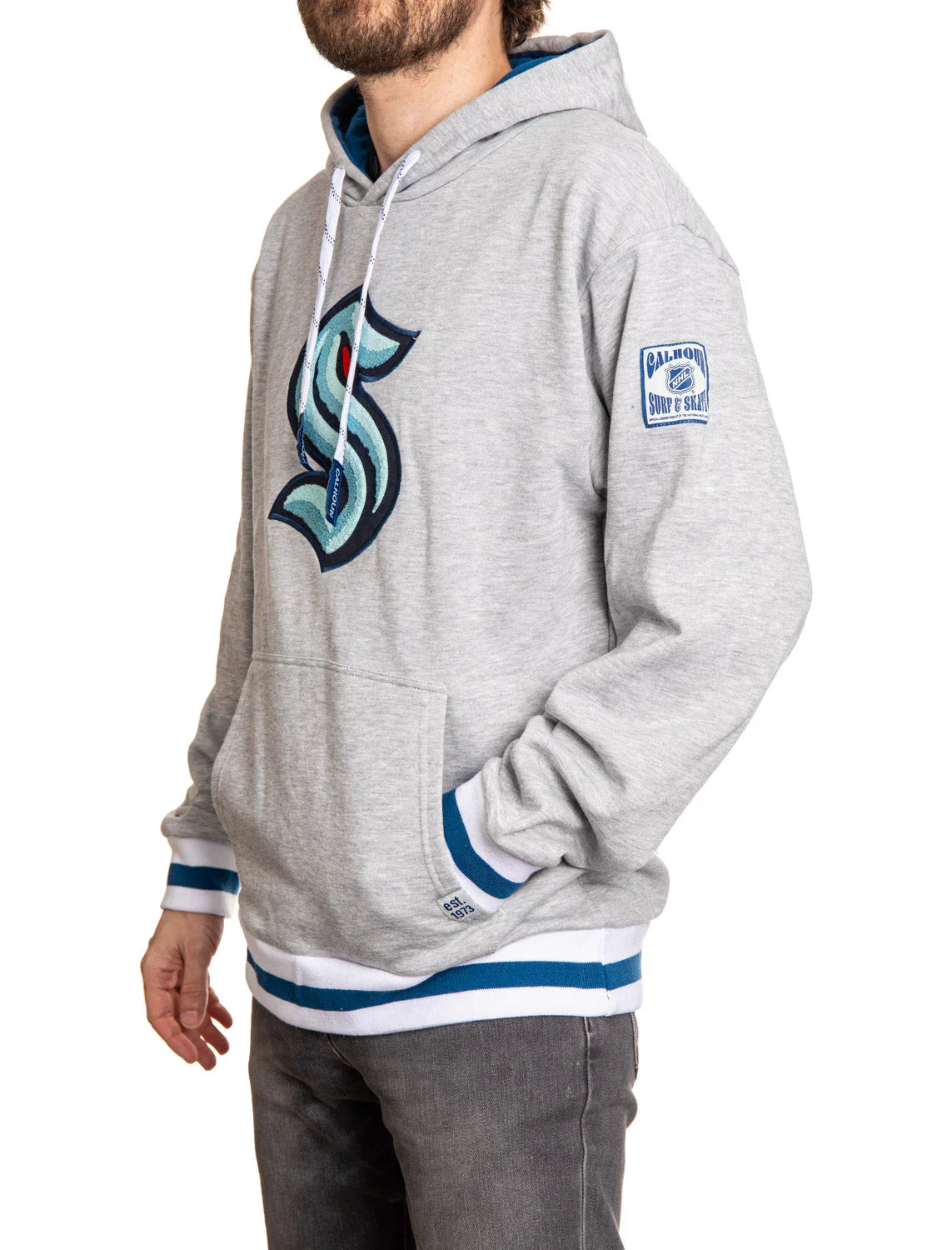 Man wearing a gray Seattle Kraken hoodie with chenille logo and blue striped cuffs