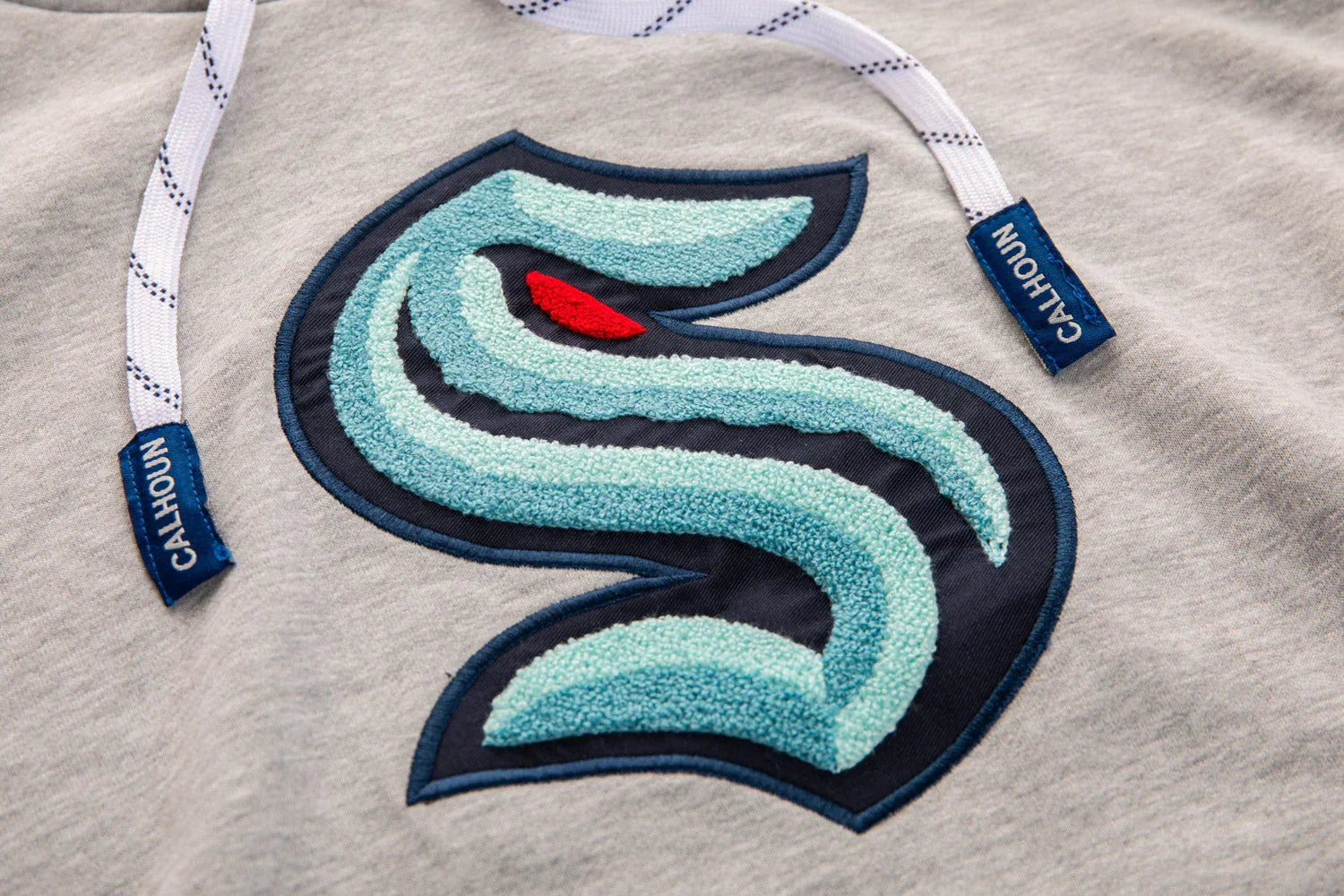 Kraken logo chenille patch on grey hoodie with Calhoun branded drawstrings
