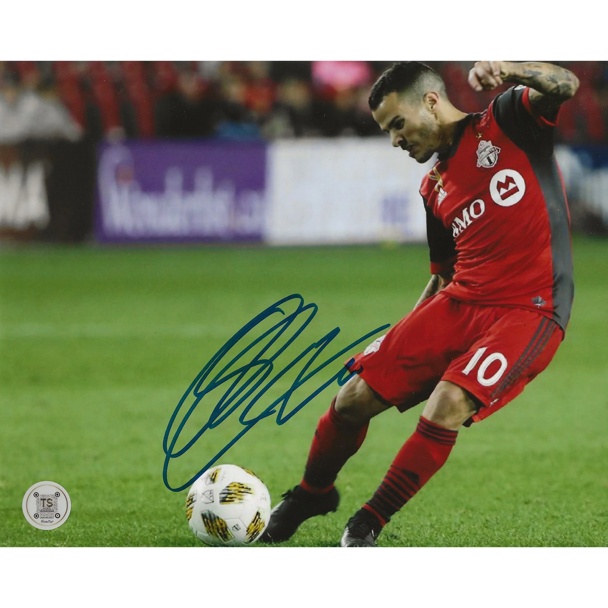 Toronto FC soccer player in red jersey kicking ball, autograph on photo, stadium background