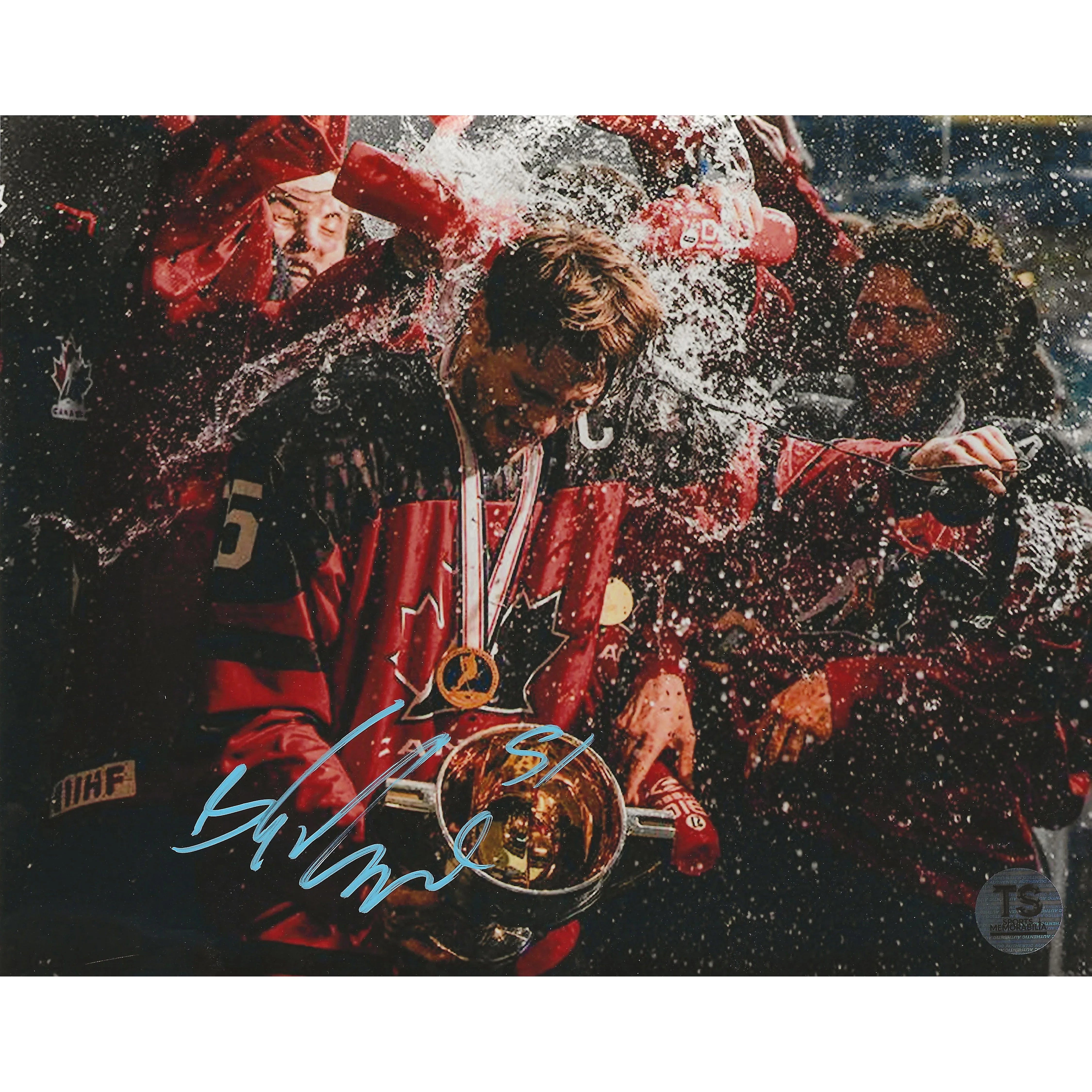 Team Canada hockey player with trophy and medal getting splashed during championship celebration
