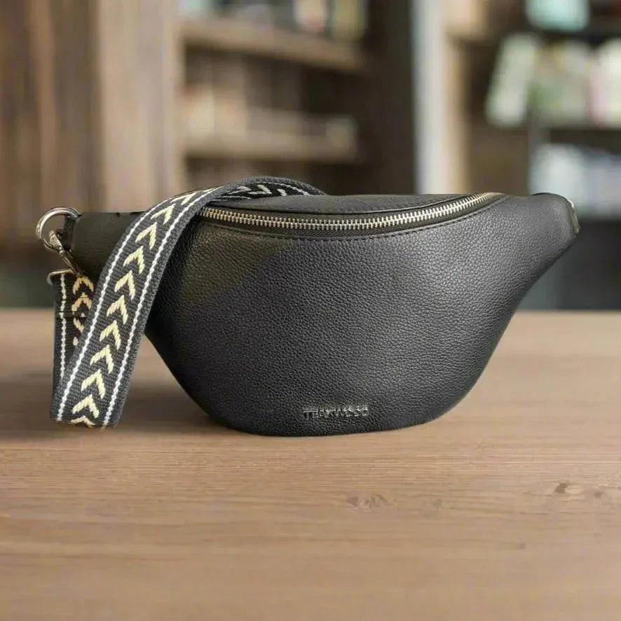 Sheep leather waist bag with patterned strap on wooden table, textured black finish