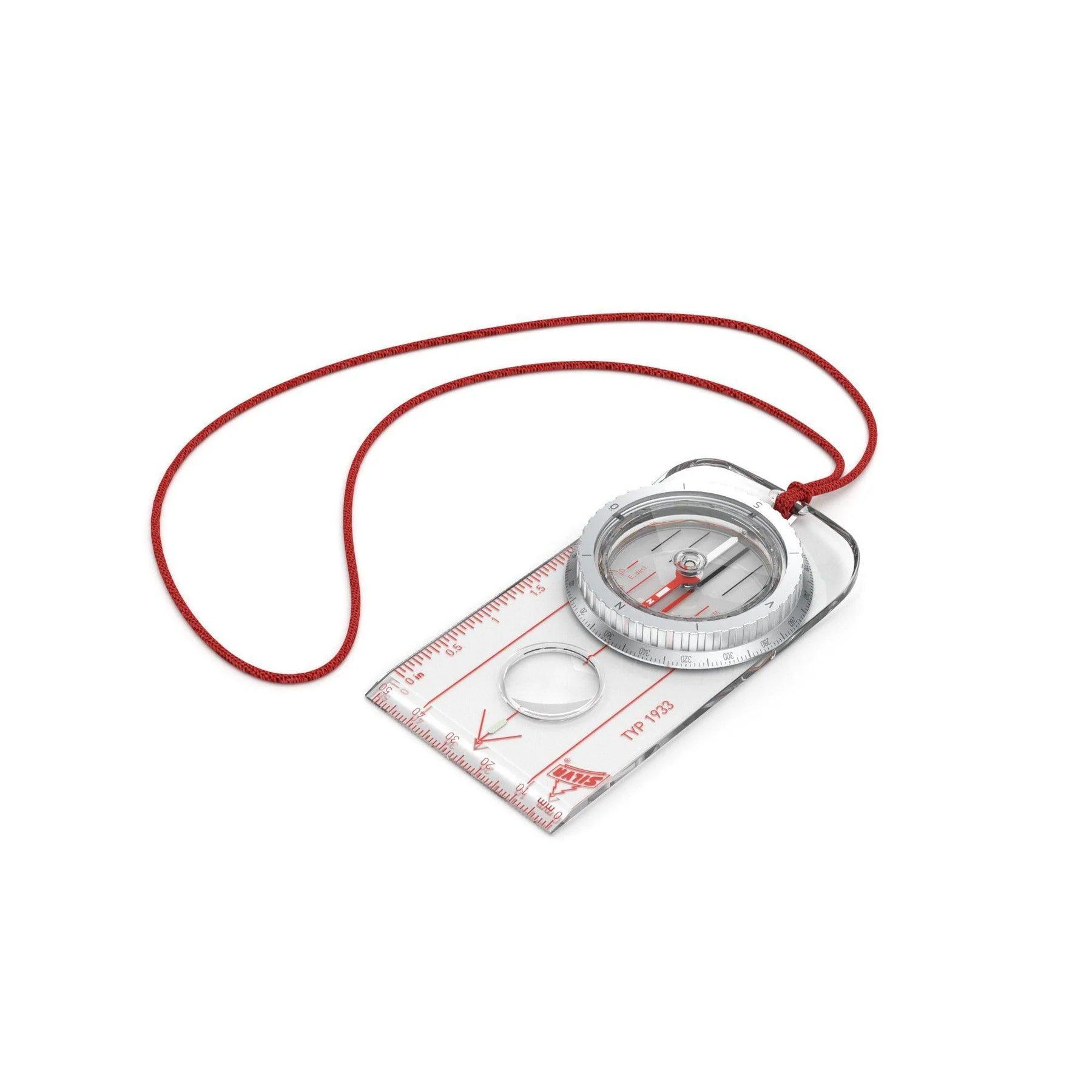 Baseplate compass with red lanyard, clear ruler, and magnifier on white background