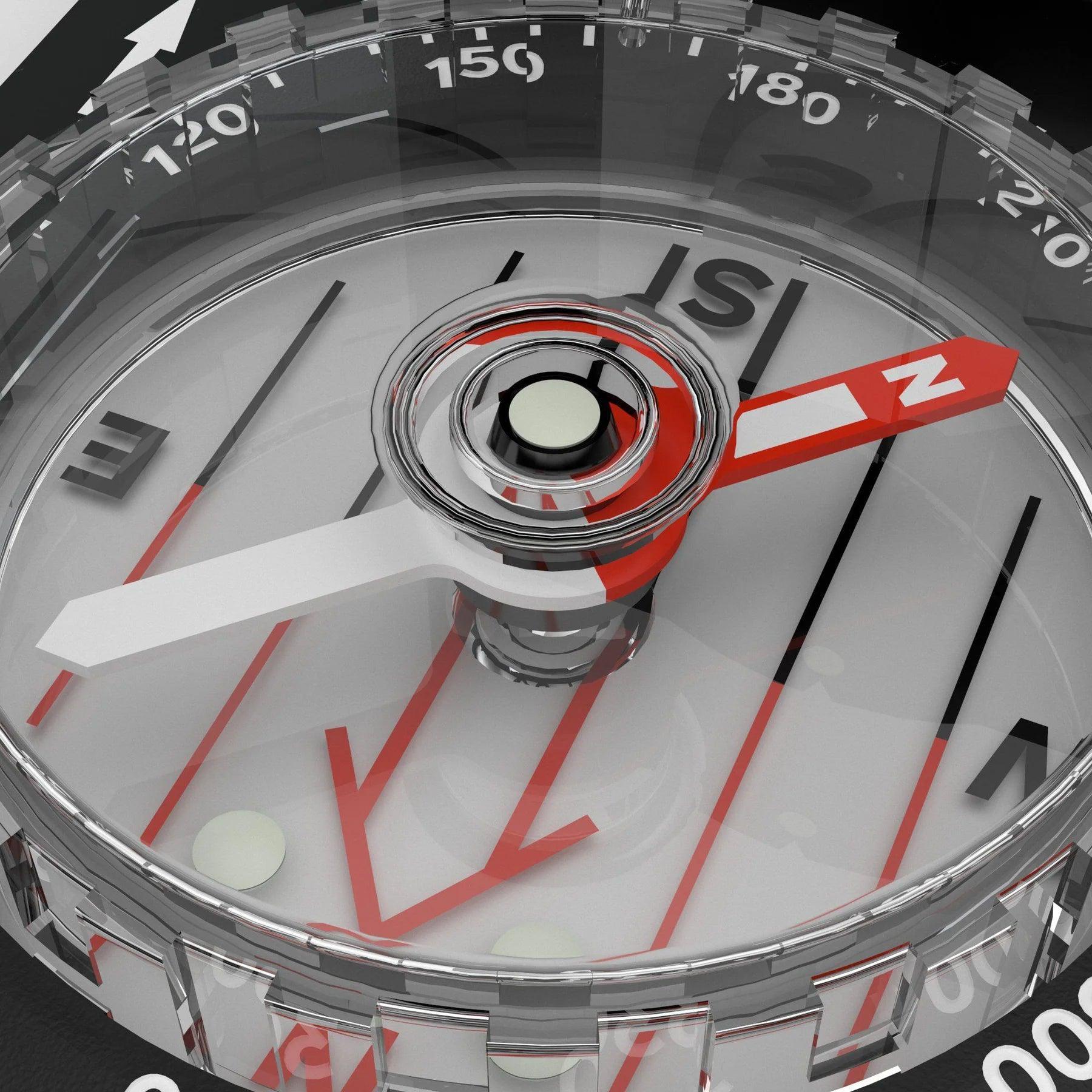 Close-up of a transparent compass with red and white needle, visible degree markings.