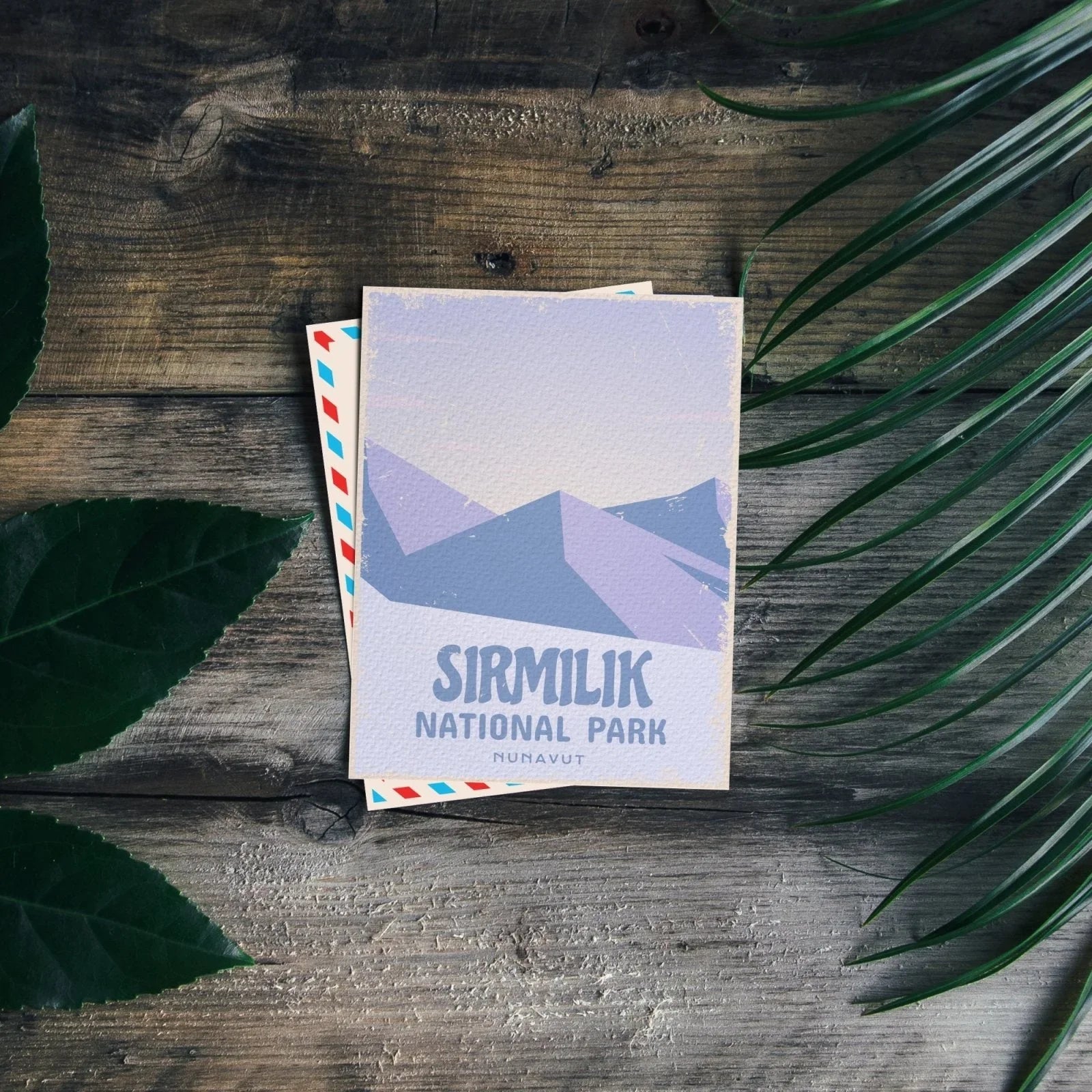 Sirmilik National Park postcard with mountain illustration on rustic wood and green leaves