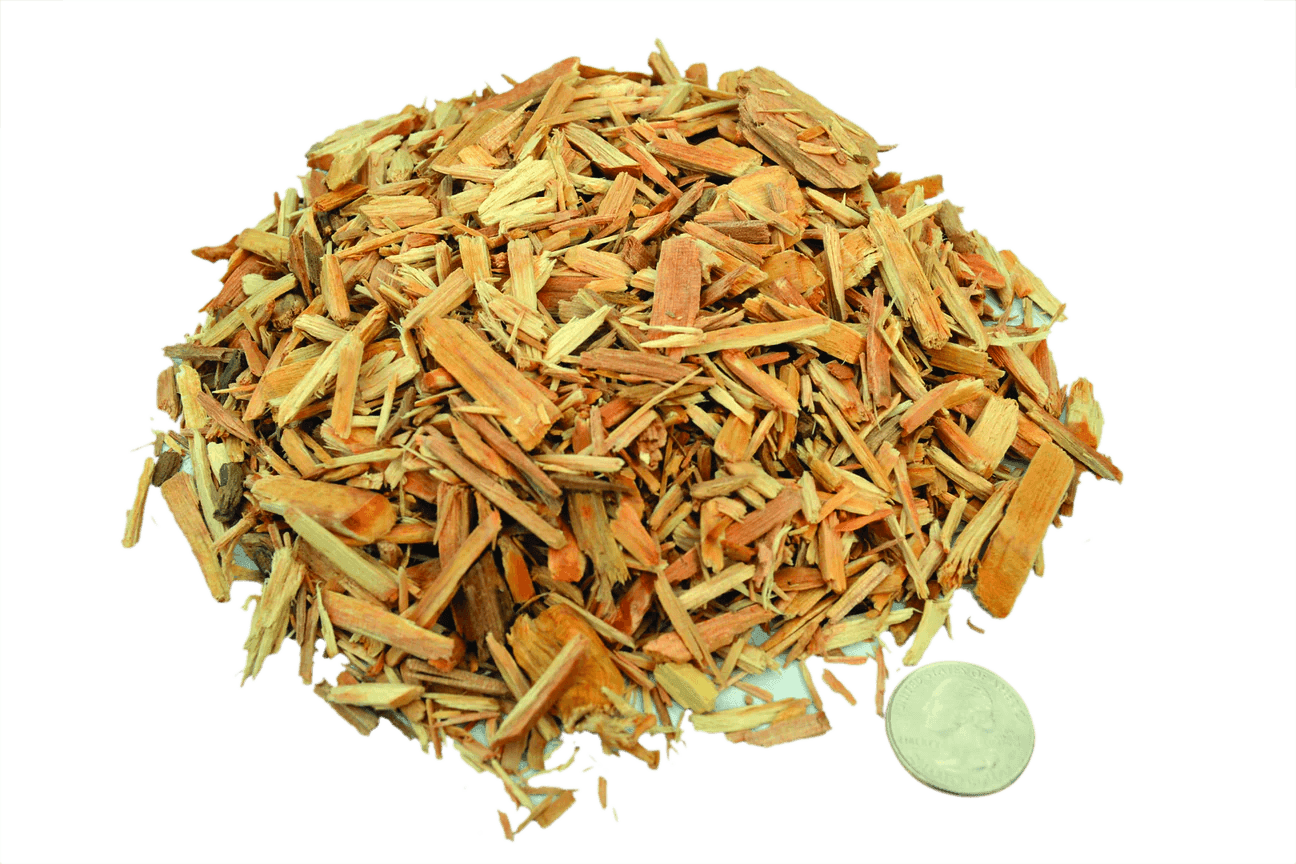 Pile of smokehouse wood chips with a quarter for size reference on a plain background