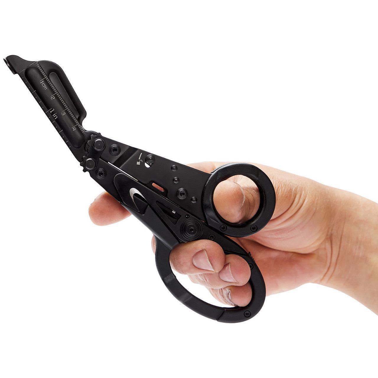 Hand holding SOG Parashears black multi-tool scissors with measurement markings
