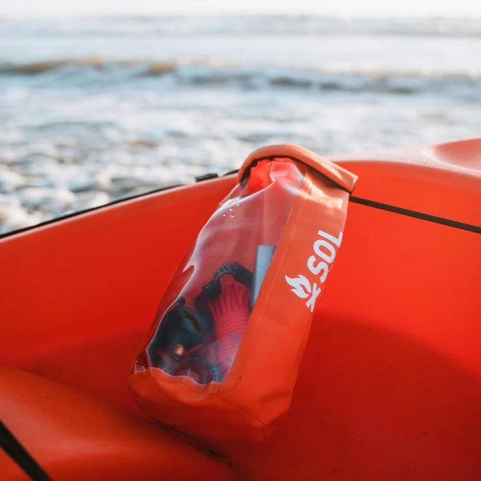 SOL adventure survival kit in orange waterproof bag on kayak by the ocean