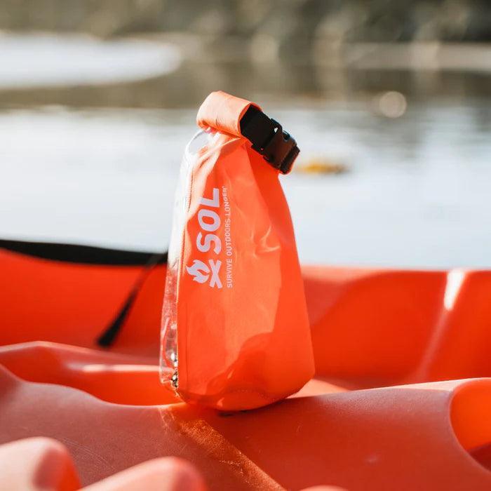 SOL adventure-ready survival kit dry bag on orange kayak by the water