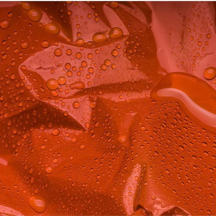 Close-up of orange waterproof emergency blanket with water droplets on surface.