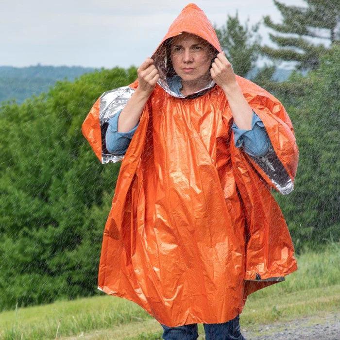 Person wearing an orange heat reflective poncho in the rain outdoors