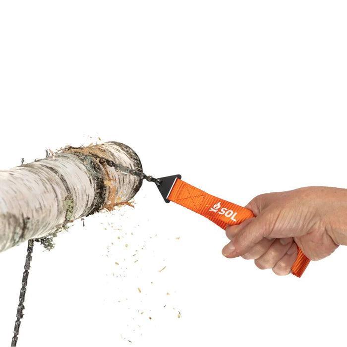 Hand using SOL pocket chain saw to cut tree branch outdoors