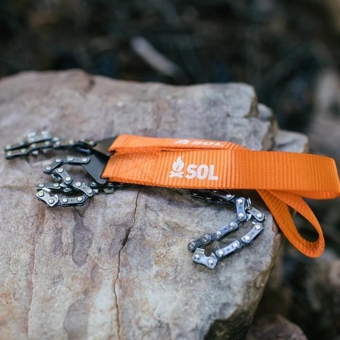 SOL pocket chain saw with orange handle on a rock, outdoor survival gear