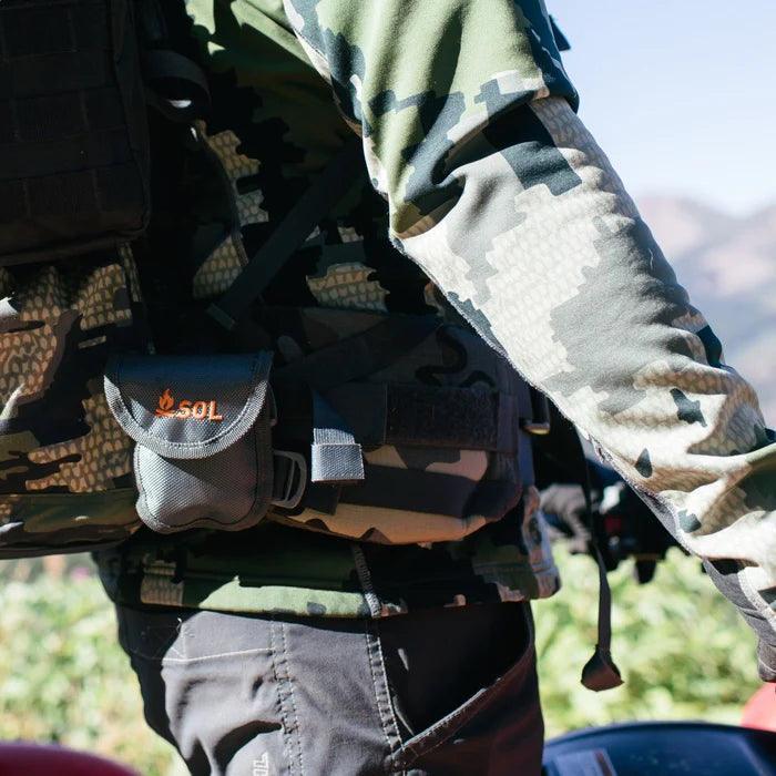 Person in camouflage wearing a SOL pocket chain saw pouch outdoors