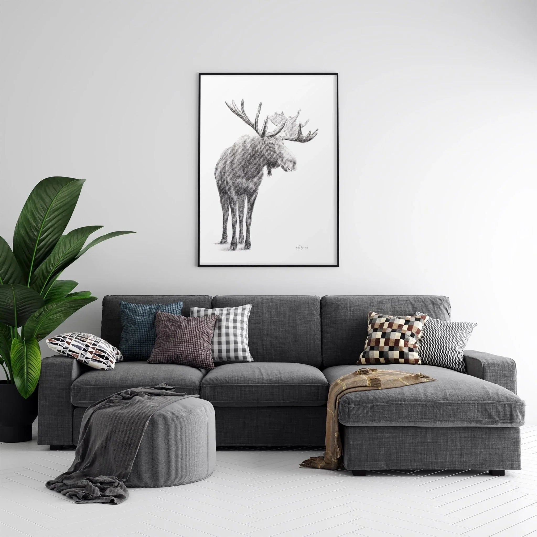 Modern living room with grey sectional sofa, decorative pillows, plant, and moose wall art